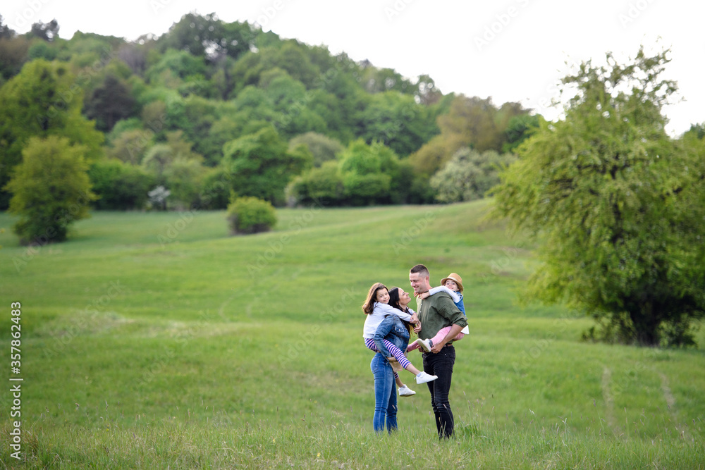 Happy family with two small daughters standing outdoors in spring nature. Happy family with two small daughters standing outdoors in spring nature.