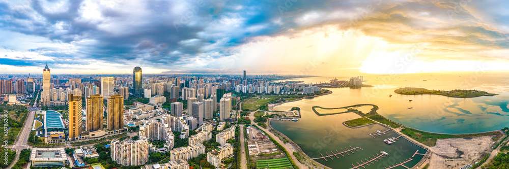 China Hainan Haikou Cityscape in the Binhai Avenue CBD Area, with Landmark Buildings , Sea Port and Evergreen Park View During Sunset. Aerial View..