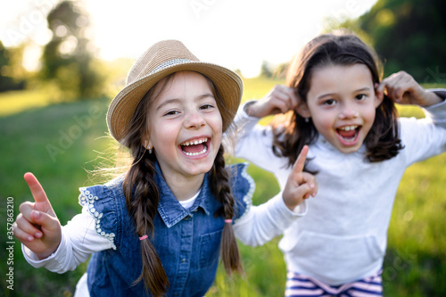 Portrait of two small girls standing outdoors in spring nature  laughing.