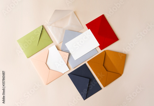 Colorful mail envelopes on beige background flat lay  top view. Mailing concept. White paper blank mockup for letters  greeting card  postcard  invitation
