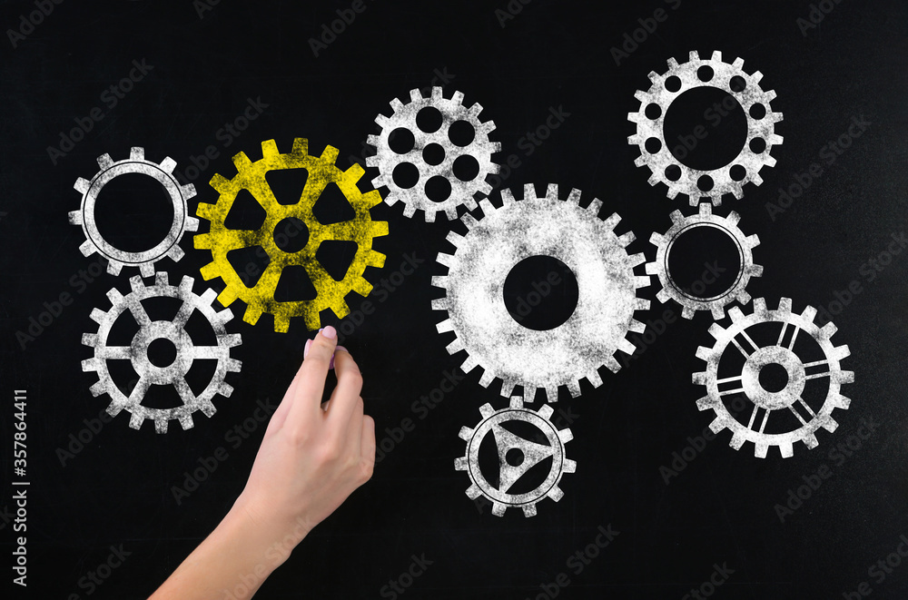 Woman drawing gear mechanism on chalkboard, closeup Woman drawing gear mechanism on chalkboard, closeup