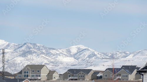 Panorama crop Neighborhood in South Jordan City against snowy Wasatch Mountains and cloudy sky