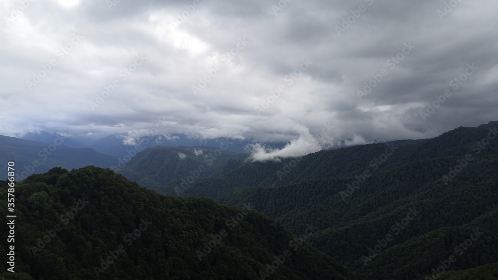 Gray clouds hang over the wooded mountains. Landscape