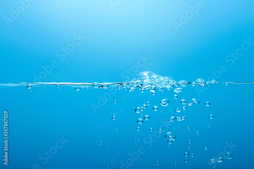 Fototapeta Naklejka Na Ścianę i Meble -  Small waves create bubbles that float in the turquoise water background.