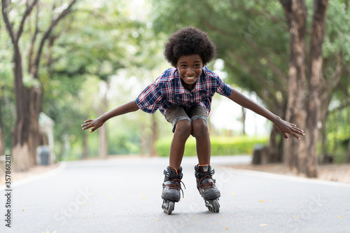 Fotografie African American young boy riding on roller skates or roller blades at outdoor, Kid playing on roller skates