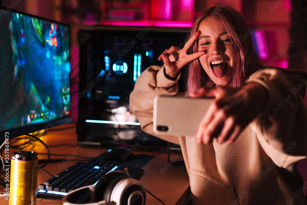 Image of girl taking selfie on cellphone while playing video game Image of girl taking selfie on cellphone while playing video game