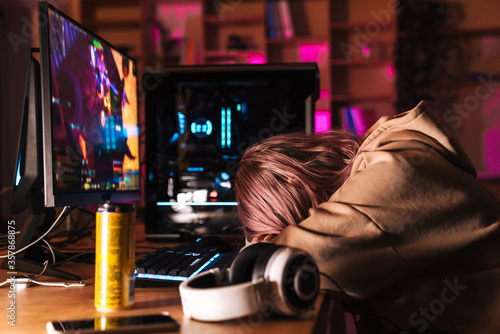 Image of exhausted girl sleeping on table while playing video game