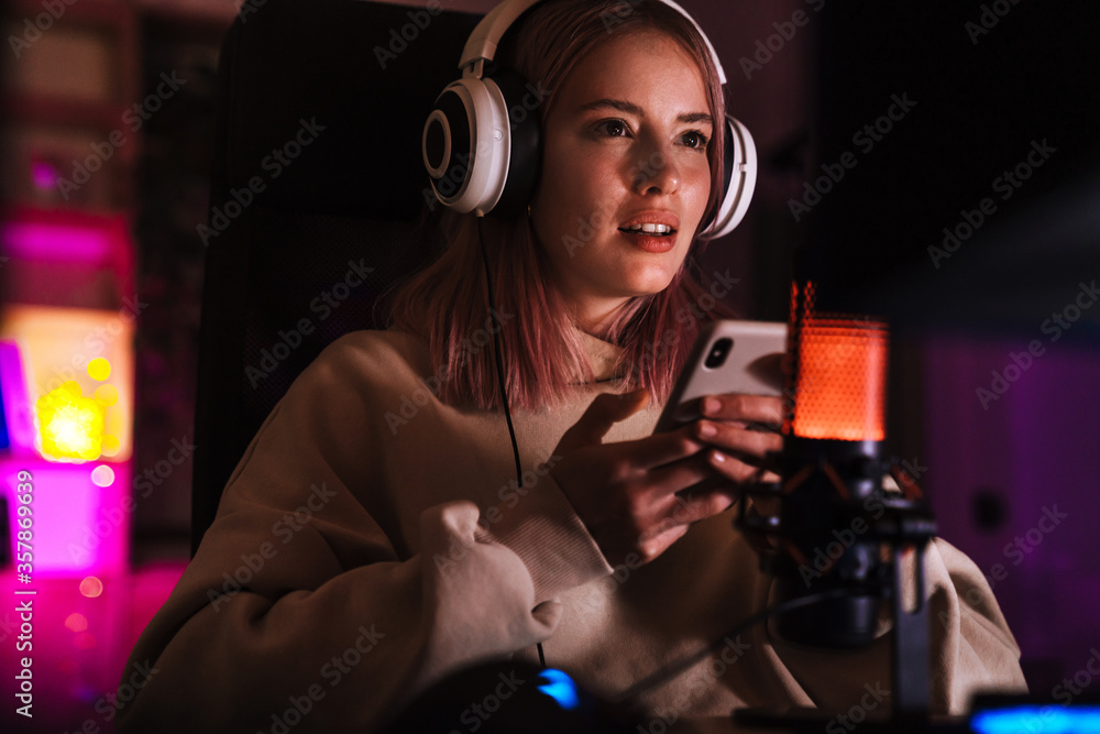 Image of concentrated girl using mobile phone while playing video game