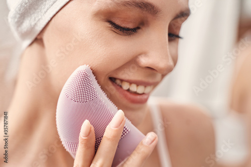 Smiling woman performing the skin cleansing procedure photo