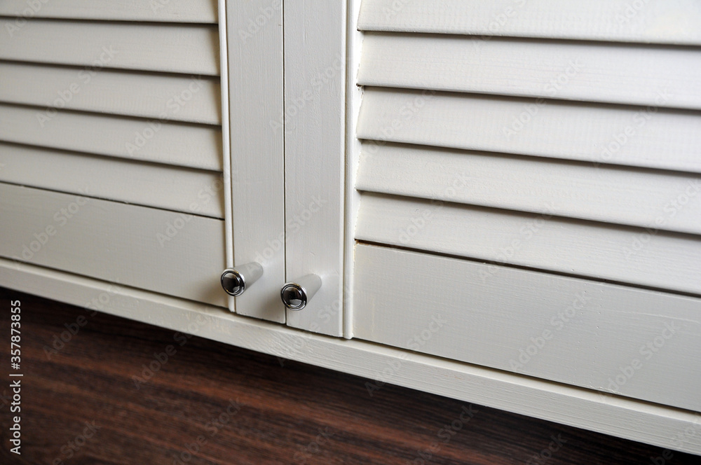 closet with louvered doors for the bathroom, toilet with stainless steel handles, close-up. closet with louvered doors for the bathroom, toilet with stainless steel handles, close-up.