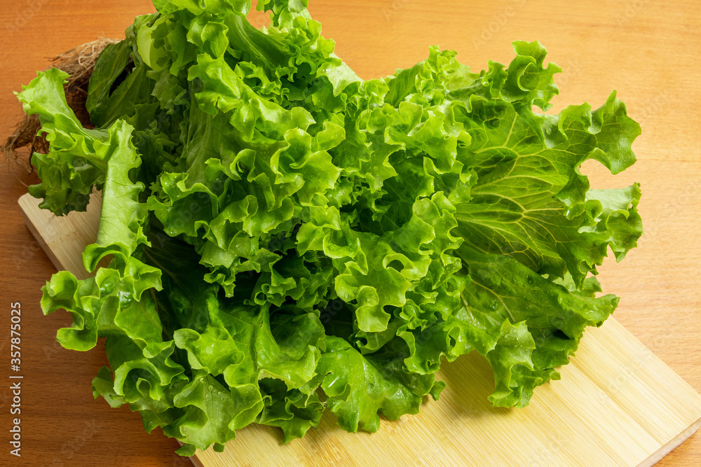 The lettuce leaves lie on a wooden cutting board. The lettuce leaves lie on a wooden cutting board.