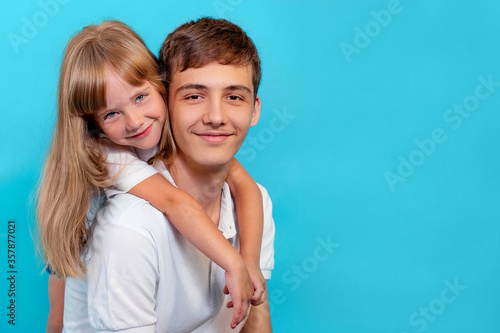 brother and sister in white t-shirts, smiling at the camera, on a blue background, the concept of family
