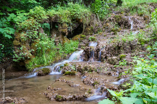Fotografía Dead and vegetated water wheel beside little waterfall