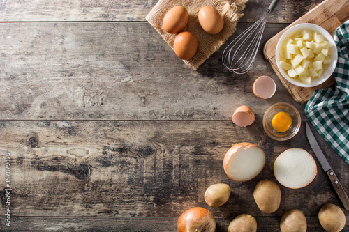 Spanish omelette tortilla ingredients: eggs, potatoes and onion on wooden table top view copy space