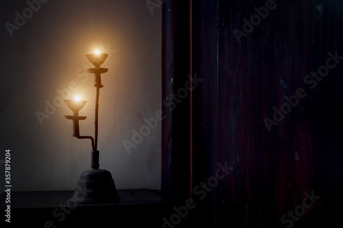 Aged candlestick with warm candle light in dark corner