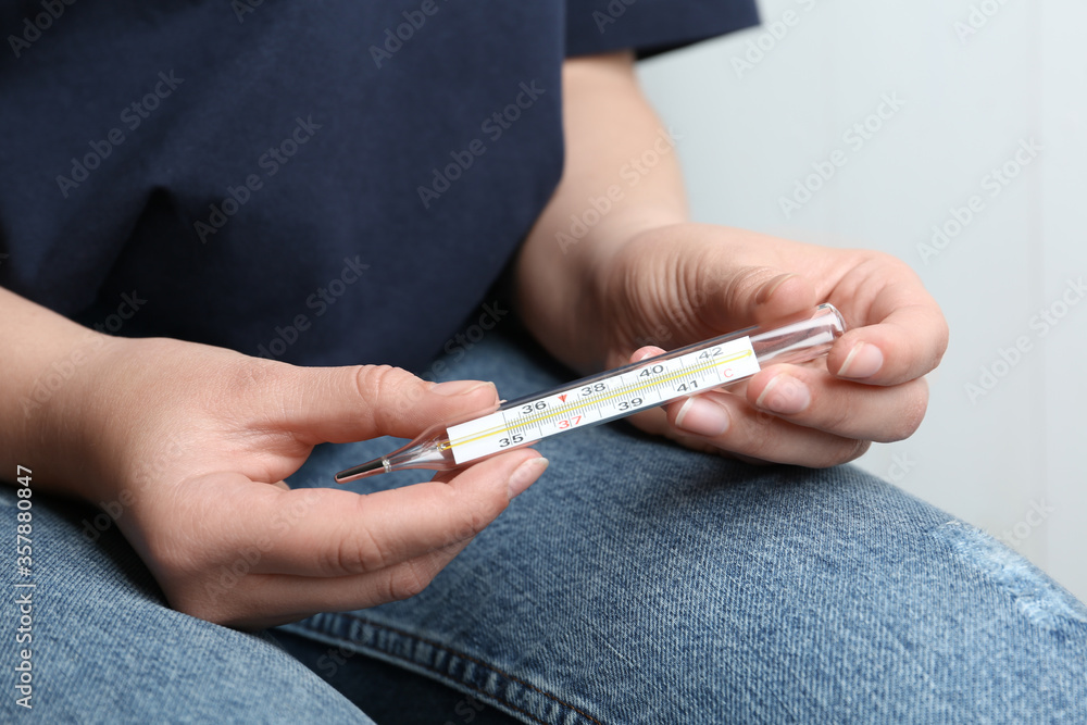 Woman with mercury thermometer on light background, closeup Woman with mercury thermometer on light background, closeup