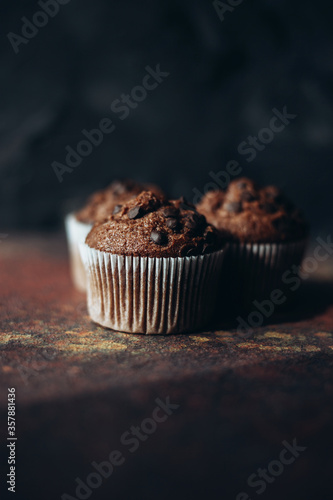 Beautiful chocolate muffins with pieces of chocolate on dark background with place for text