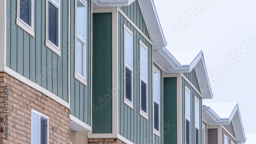 Panorama frame Vertical siding and stone brick wall at the townhomes upper storey against sky © Jason