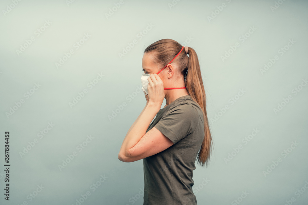 A girl is putting on a protective mask. Respiratory protection from coronavirus. Personal protective equipment for a pandemic of a viral infection. Covid-19. A girl is putting on a protective mask. Respiratory protection from coronavirus. Personal protective equipment for a pandemic of a viral infection. Covid-19.