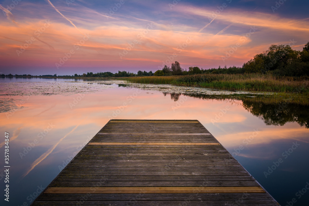 Naklejka premium wooden bridge over lake at sunset