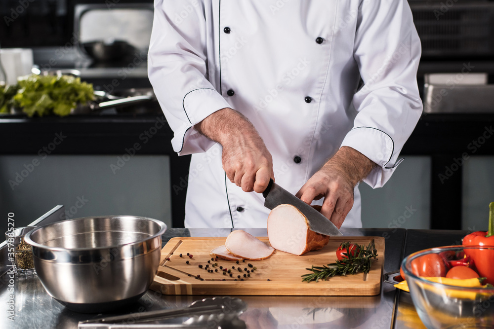 © stockbusters - Chef hands with knife slice meat at kitchen. Closeup chef hands cutting hum.