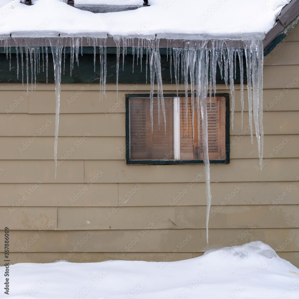 Square Snow covered roof with row of icicles over windows and wooden wall in Park City Square Snow covered roof with row of icicles over windows and wooden wall in Park City