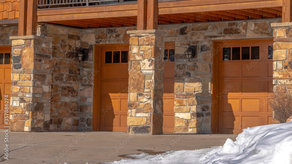 Panorama Garage entrance of a home with stone brick wall and balcony in snowy Park City