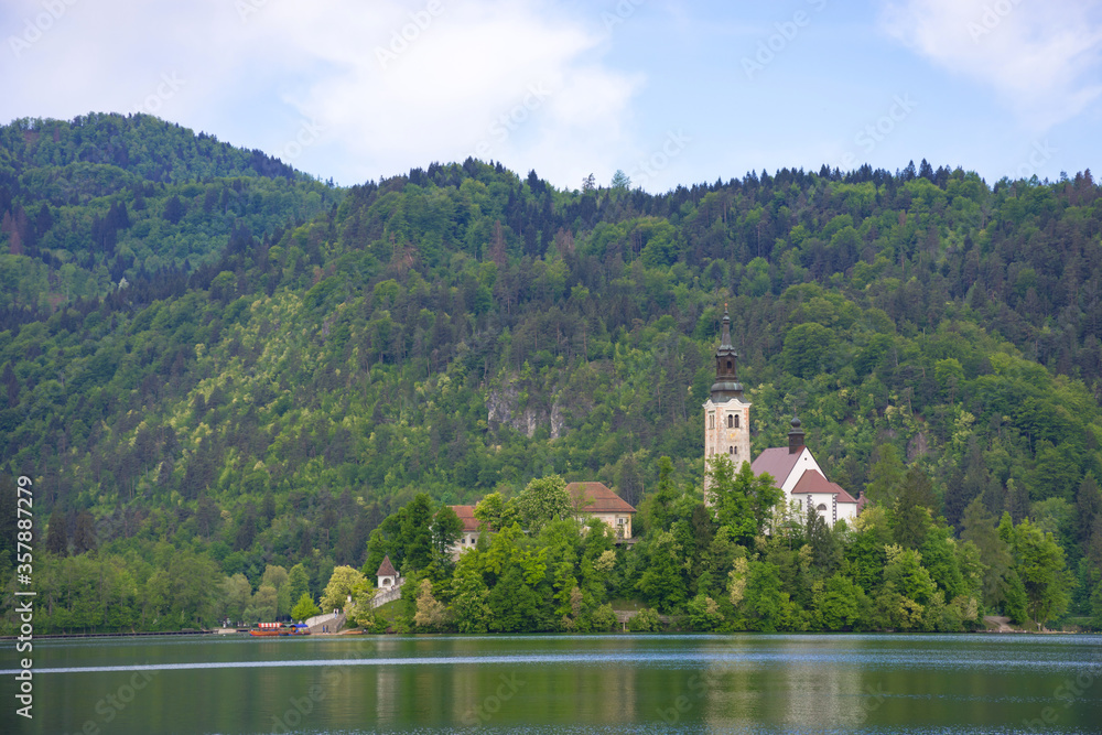 Obraz premium Morning at Lake Bled and Julian Alps in the background. The lake island and charming little church dedicated to the Assumption of Mary are famous tourist attraction in Slovenia