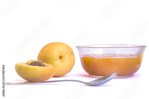 Ripe sweet apricots, glass bowl with homemade jam or marmalade and tea spoon on white background.  Food ingredient. Fruits and vegetables. Homemade recipe.