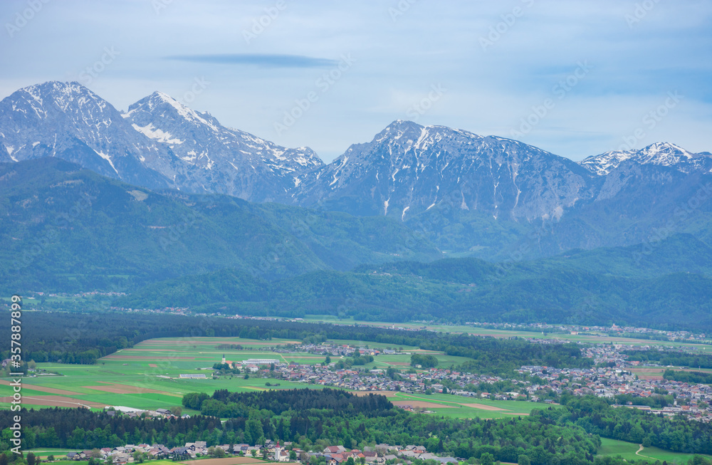 Obraz premium Slovenian countryside in spring with charming little village and Julian Alps in the background