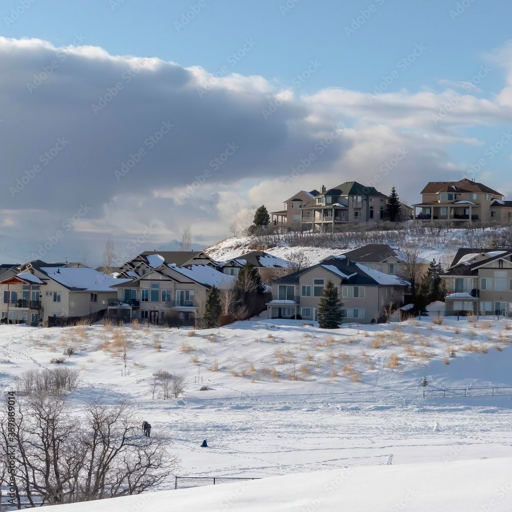 Square Wasatch Mountain in winter with houses on sunlit acres of snow covered terrain