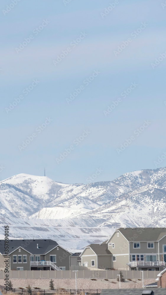 Vertical Neighborhood in South Jordan City against snowy Wasatch Mountains and cloudy sky