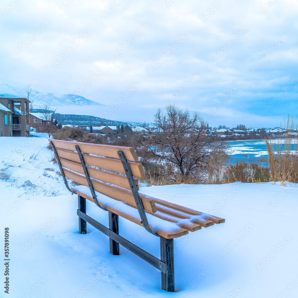 Square crop Empty outdoor bench on snowy terrain overlooking frozen Utah Lake in winter