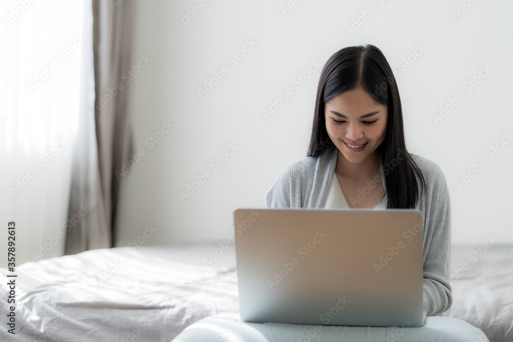 Young beautiful woman works from home with laptop computer at the the bedroom, living room.Communication and video conference concept Young beautiful woman works from home with laptop computer at the the bedroom, living room.Communication and video conference concept