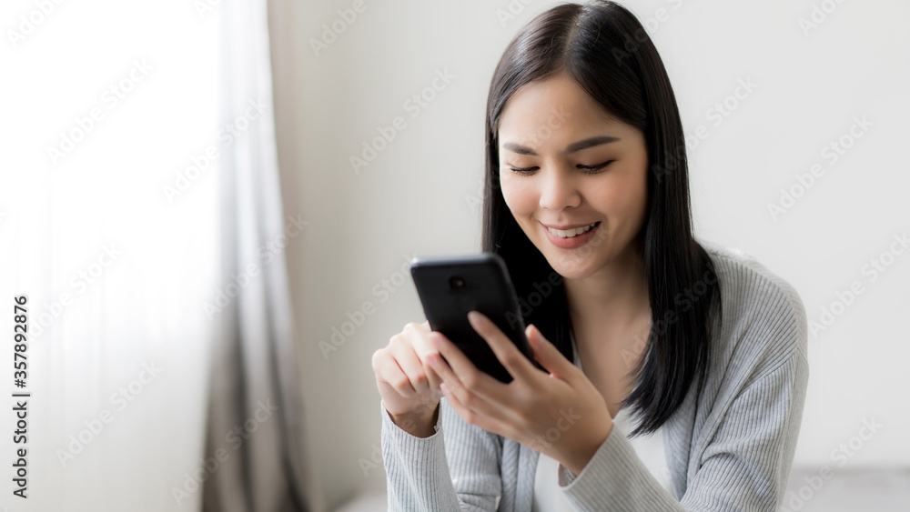Young beautiful woman checking social media with mobile at the the bedroom, living room. Communication and technology concept. Young beautiful woman checking social media with mobile at the the bedroom, living room. Communication and technology concept.