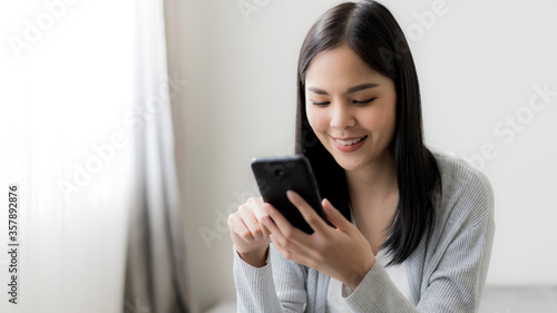 Young beautiful woman checking social media with mobile at the the bedroom, living room. Communication and technology concept.