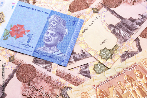A close up image of a blue one Malaysian ringgit bank note on a bed of Egyptian one pound bank notes close up in macro