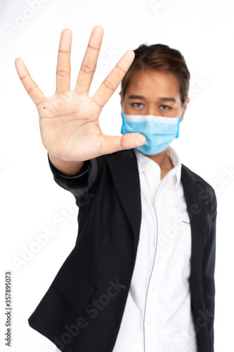 Asian businesswoman wearing face mask in formal black suit jacket, looking at camera, make hand stop with five finger, studio lighting isolated on white background, coronavirus, COVID19 concept 