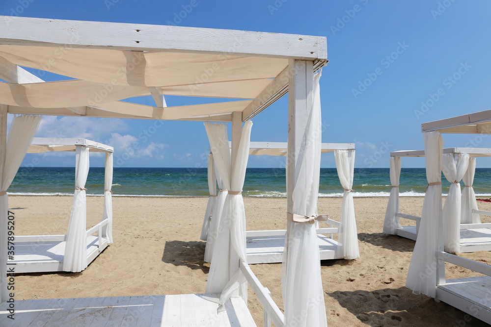 white canopy beach beds by the sea on a white sand beach in summer