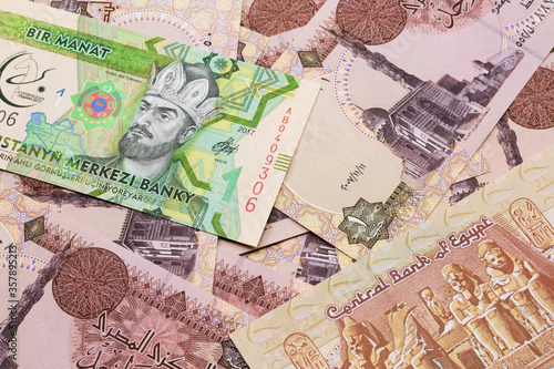 A one manat bank note from Turkmenistan close up in macro with an assortment of Egyptian one pound bank notes.