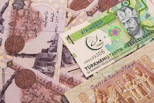 A one manat bank note from Turkmenistan close up in macro with an assortment of Egyptian one pound bank notes.