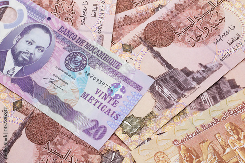 A close up image of a purple, twenty metical bank note from Mozambique on a background of Egyptian one pound bank notes