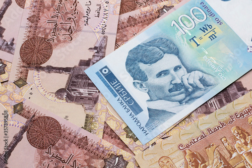 A close up of a blue and white, one hundred Serbian dinar bank note on a background of Egyptian one pound bank notes