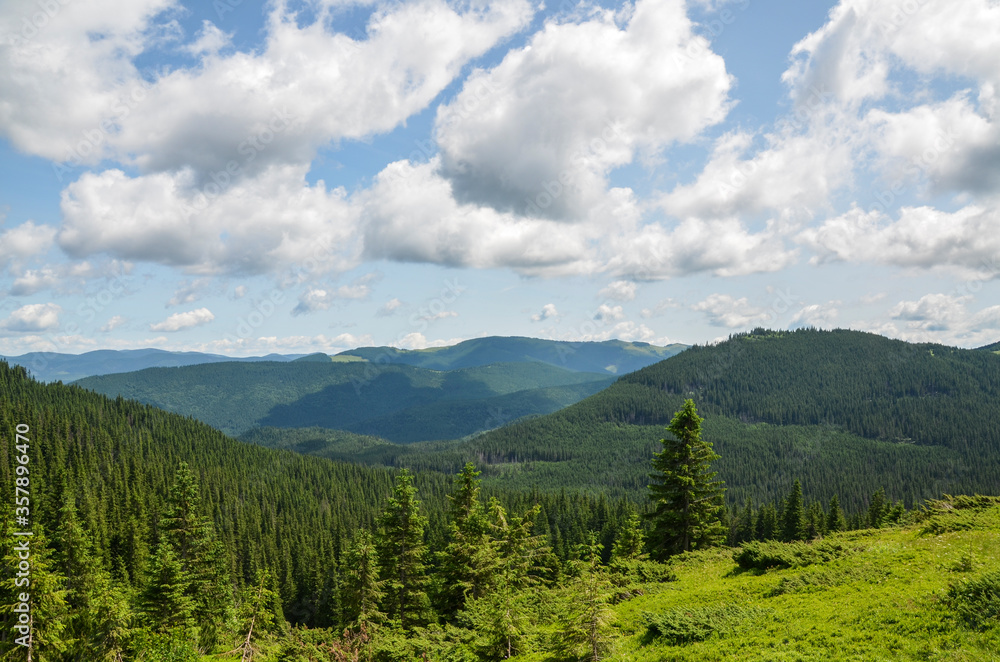Scenic skyscape with blue sky full of windy clouds, and beautiful green mountains. Carpathians, Ukraine. Natural landscape