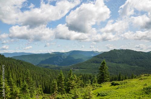 Scenic skyscape with blue sky full of windy clouds, and beautiful green mountains. Carpathians, Ukraine. Natural landscape © Dmytro