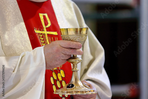 Priest holds the chalice while celebrating the mass and empty space for text