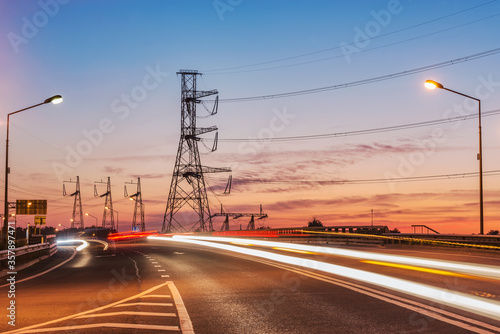 New highway and high-voltage towers at sunset time.