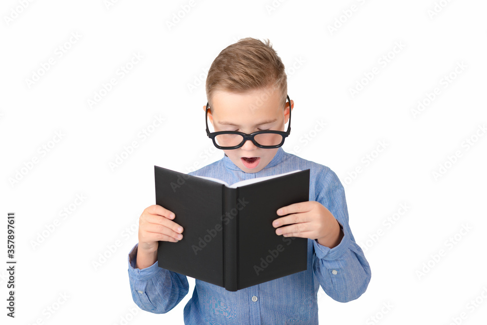 Cute dreamy schoolboy reads book and wearing glasses while standing in the studio, isolated over white Cute dreamy schoolboy reads book and wearing glasses while standing in the studio, isolated over white