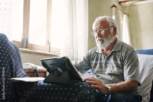 An old man using a tablet photo