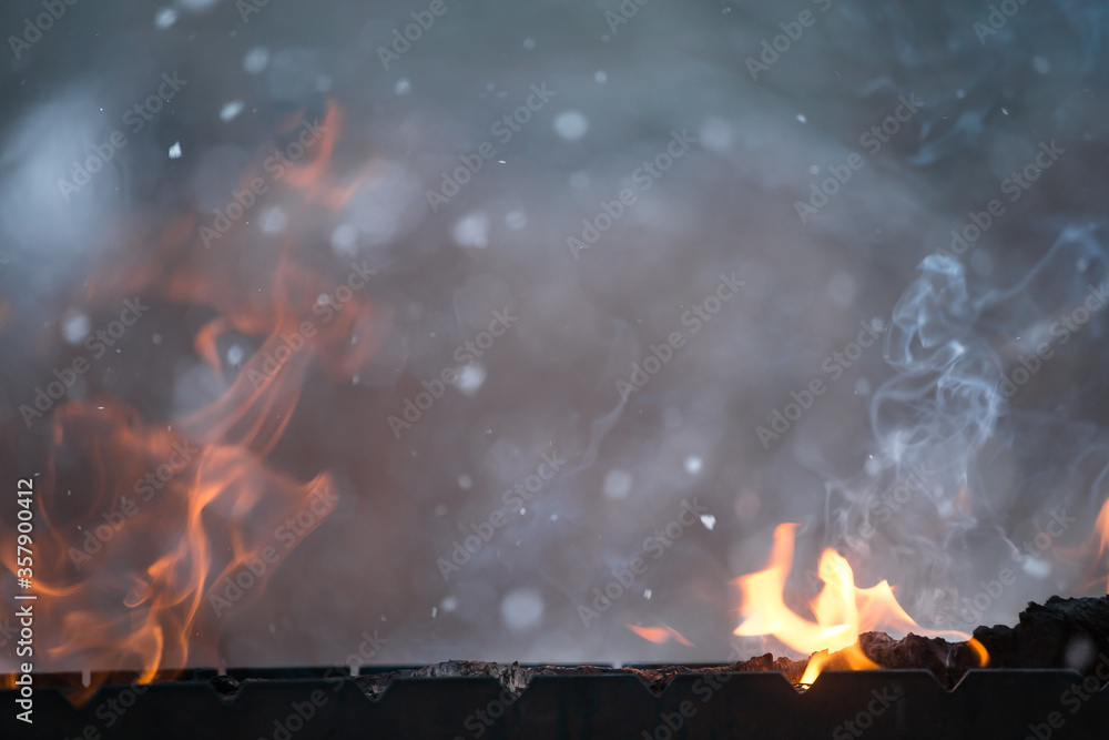 Obraz premium Fire flames burst from the grill on the background of snow